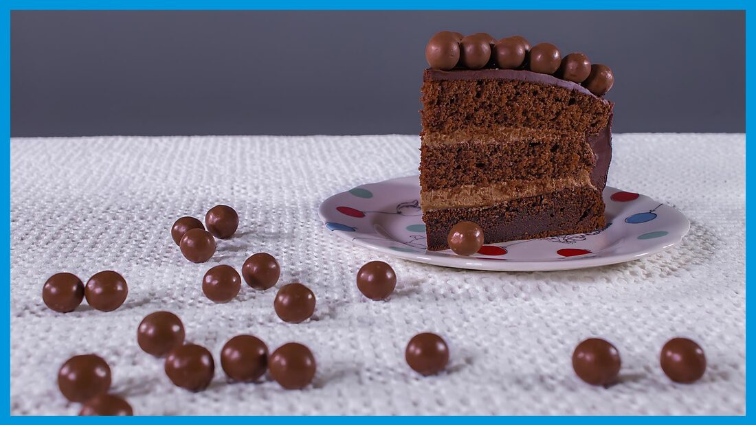 A slice of chocolate malteser cake and loose maltesers on the table. Silverbox Food photography workshop